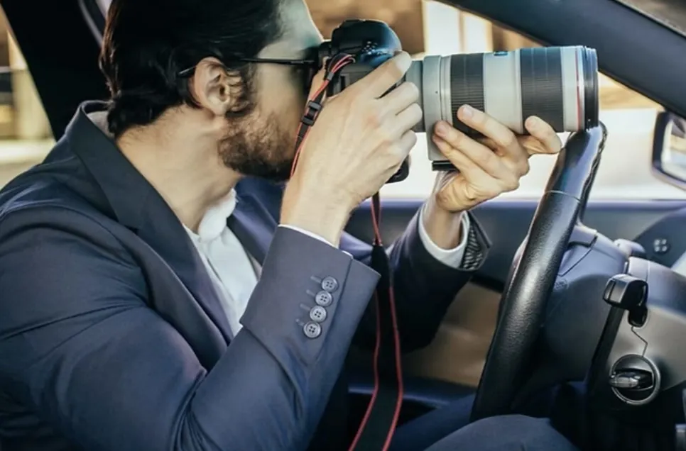 Licensed investigator photographing from a vehicle with a telephoto camera